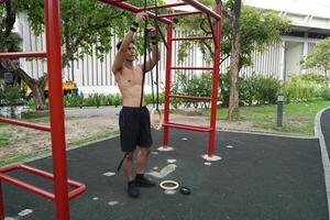 Asian man practicing gymnastics, doing gymnastics bar and hoop exercises and stretching, resting for sports. photo