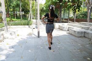 Asian woman dancing in the middle of a park photo