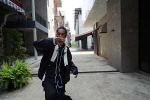 ASian man is dancing in hip hop style at outdoor space. Professional solo dancer is performing in public area. photo