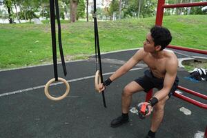 Asian man practicing gymnastics, doing gymnastics bar and hoop exercises and stretching, resting for sports. photo