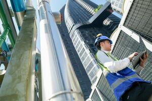 Industrial engineer adjusting pipeline valve with radio communication on construction site. Engineer on urban construction site using radio to coordinate with team on a sunny industrial rooftop. photo