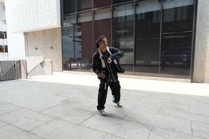 ASian man is dancing in hip hop style at outdoor space. Professional solo dancer is performing in public area. photo