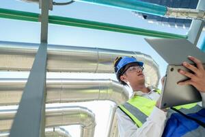 Industrial engineer adjusting pipeline valve with radio communication on construction site. Engineer on urban construction site using radio to coordinate with team on a sunny industrial rooftop. photo