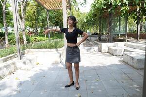 Asian woman dancing in the middle of a park photo