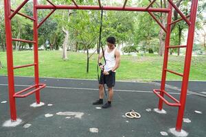 Asian man practicing gymnastics doing gymnastics bar and hoop exercises and stretching and resting for sports. photo