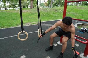 Asian man practicing gymnastics, doing gymnastics bar and hoop exercises and stretching, resting for sports. photo