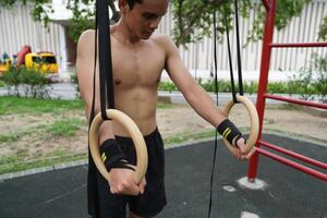Asian man practicing gymnastics, doing gymnastics bar and hoop exercises and stretching, resting for sports. photo