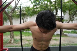 Asian man practicing gymnastics, doing gymnastics bar and hoop exercises and stretching, resting for sports. photo