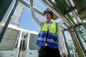 Industrial engineer adjusting pipeline valve with radio communication on construction site. Engineer on urban construction site using radio to coordinate with team on a sunny industrial rooftop. photo