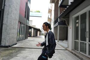 ASian man is dancing in hip hop style at outdoor space. Professional solo dancer is performing in public area. photo