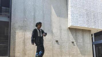 ASian man is dancing in hip hop style at outdoor space. Professional solo dancer is performing in public area. photo