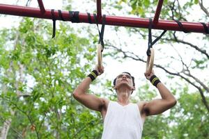 Asian man practicing gymnastics doing gymnastics bar and hoop exercises and stretching and resting for sports. photo