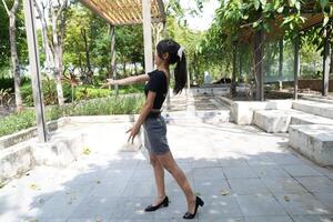 Asian woman dancing in the middle of a park photo