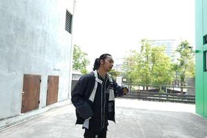 ASian man is dancing in hip hop style at outdoor space. Professional solo dancer is performing in public area. photo