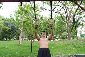 Asian man practicing gymnastics, doing gymnastics bar and hoop exercises and stretching, resting for sports. photo