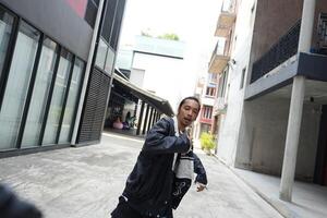 ASian man is dancing in hip hop style at outdoor space. Professional solo dancer is performing in public area. photo