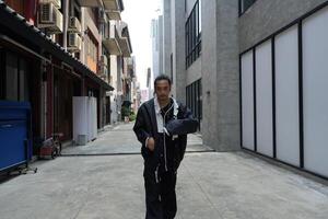 ASian man is dancing in hip hop style at outdoor space. Professional solo dancer is performing in public area. photo