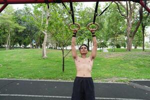 Asian man practicing gymnastics, doing gymnastics bar and hoop exercises and stretching, resting for sports. photo