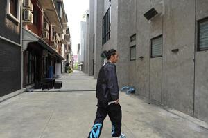 ASian man is dancing in hip hop style at outdoor space. Professional solo dancer is performing in public area. photo