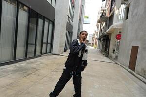ASian man is dancing in hip hop style at outdoor space. Professional solo dancer is performing in public area. photo