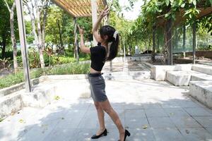 Asian woman dancing in the middle of a park photo