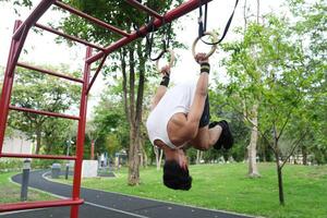 Asian man practicing gymnastics, doing gymnastics bar and hoop exercises and stretching, resting for sports. photo