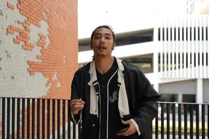ASian man is dancing in hip hop style at outdoor space. Professional solo dancer is performing in public area. photo