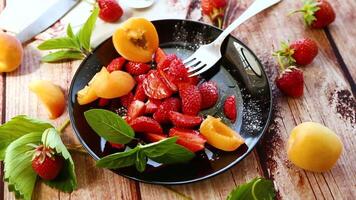 fresh fruit salad of ripe strawberries and apricots, on a light wooden table video