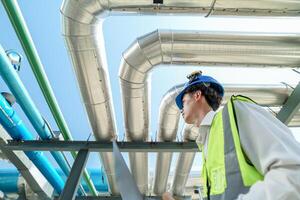Industrial engineer adjusting pipeline valve with radio communication on construction site. Engineer on urban construction site using radio to coordinate with team on a sunny industrial rooftop. photo