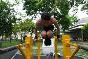 Asian man practicing gymnastics, doing gymnastics bar and hoop exercises and stretching, resting for sports. photo