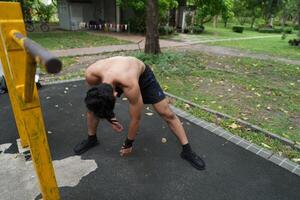 Asian man practicing gymnastics, doing gymnastics bar and hoop exercises and stretching, resting for sports. photo