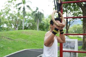 Asian man practicing gymnastics, doing gymnastics bar and hoop exercises and stretching, resting for sports. photo