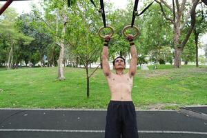 Asian man practicing gymnastics, doing gymnastics bar and hoop exercises and stretching, resting for sports. photo