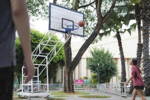 The male and female basketball players practice using the ball in the park court diligently and happily. photo