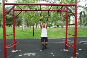 Asian man practicing gymnastics doing gymnastics bar and hoop exercises and stretching and resting for sports. photo