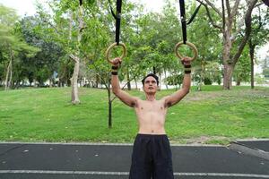 Asian man practicing gymnastics, doing gymnastics bar and hoop exercises and stretching, resting for sports. photo