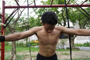 Asian man practicing gymnastics, doing gymnastics bar and hoop exercises and stretching, resting for sports. photo