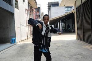 ASian man is dancing in hip hop style at outdoor space. Professional solo dancer is performing in public area. photo