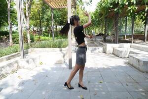 Asian woman dancing in the middle of a park photo