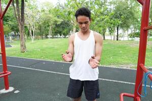 Asian man practicing gymnastics doing gymnastics bar and hoop exercises and stretching and resting for sports. photo