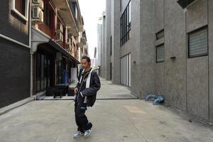 ASian man is dancing in hip hop style at outdoor space. Professional solo dancer is performing in public area. photo