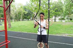 Asian man practicing gymnastics doing gymnastics bar and hoop exercises and stretching and resting for sports. photo