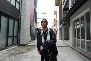 ASian man is dancing in hip hop style at outdoor space. Professional solo dancer is performing in public area. photo
