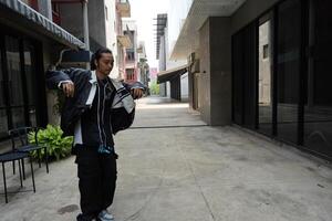 ASian man is dancing in hip hop style at outdoor space. Professional solo dancer is performing in public area. photo