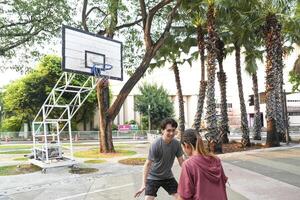 The male and female basketball players practice using the ball in the park court diligently and happily. photo