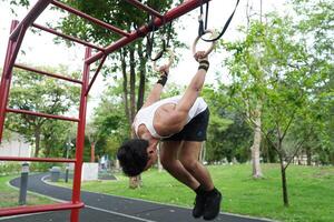 Asian man practicing gymnastics, doing gymnastics bar and hoop exercises and stretching, resting for sports. photo