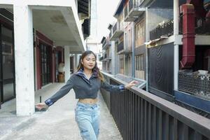 asiático mujer hacer estilo libre cadera salto y breakdance en un público espacio en el medio de el ciudad. con un alegre y contento actitud foto