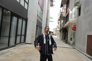 ASian man is dancing in hip hop style at outdoor space. Professional solo dancer is performing in public area. photo
