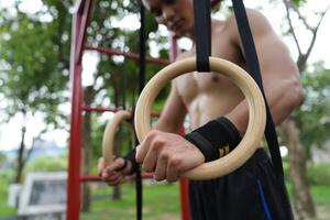 Asian man practicing gymnastics, doing gymnastics bar and hoop exercises and stretching, resting for sports. photo