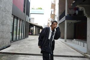 ASian man is dancing in hip hop style at outdoor space. Professional solo dancer is performing in public area. photo